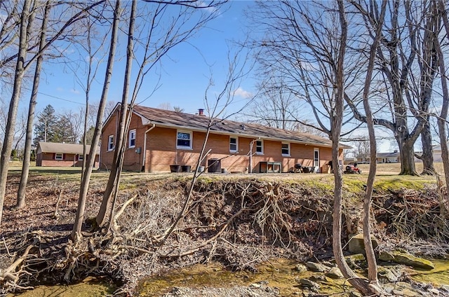 rear view of house featuring brick siding and a chimney