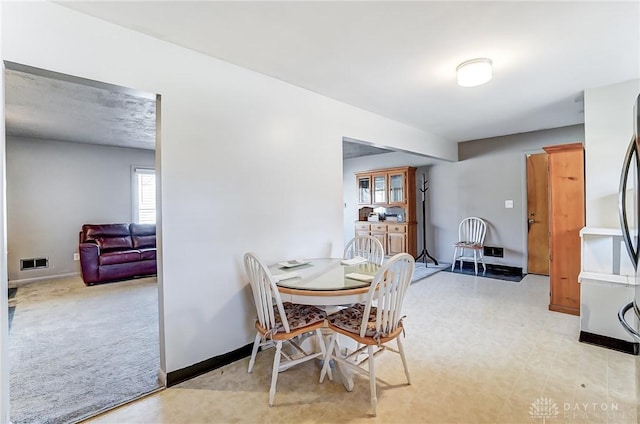 dining space featuring light carpet, visible vents, and baseboards