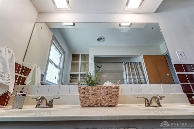 full bathroom featuring double vanity, tasteful backsplash, visible vents, and a sink