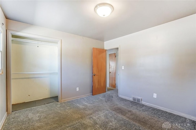 unfurnished bedroom featuring a closet, dark carpet, visible vents, and baseboards