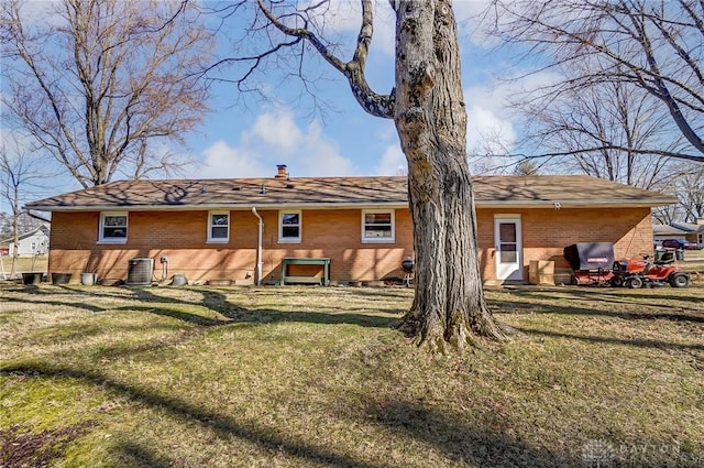 back of house featuring a yard, brick siding, and a chimney