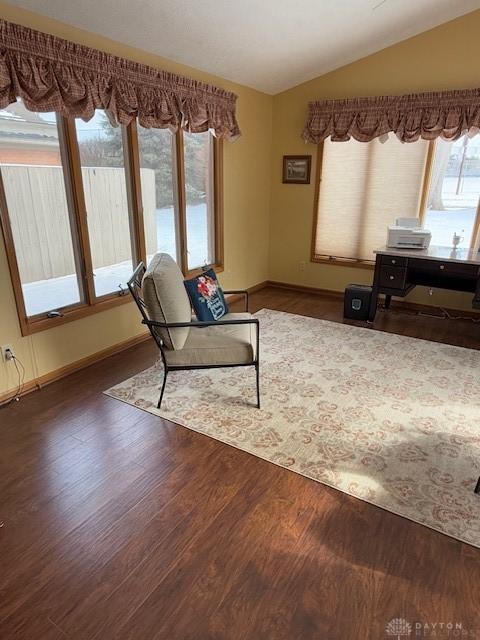 living area featuring dark wood finished floors, vaulted ceiling, and baseboards