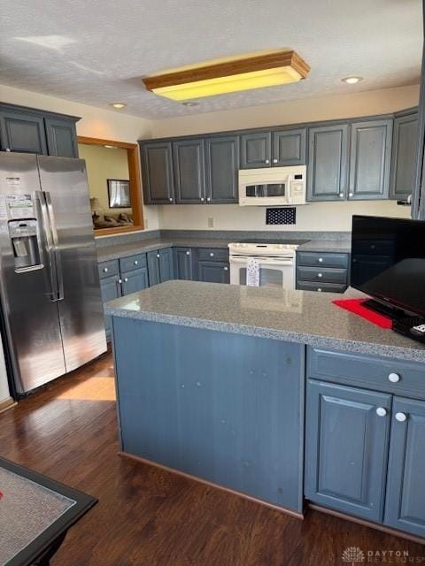 kitchen with white appliances, dark wood-type flooring, and recessed lighting