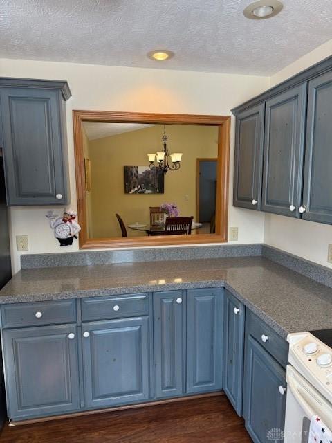 kitchen featuring lofted ceiling, blue cabinets, white range with electric stovetop, dark countertops, and an inviting chandelier