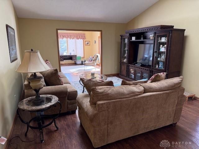 living room with vaulted ceiling, dark wood-type flooring, and baseboards