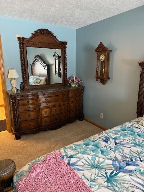 bedroom with light carpet, a textured ceiling, and baseboards