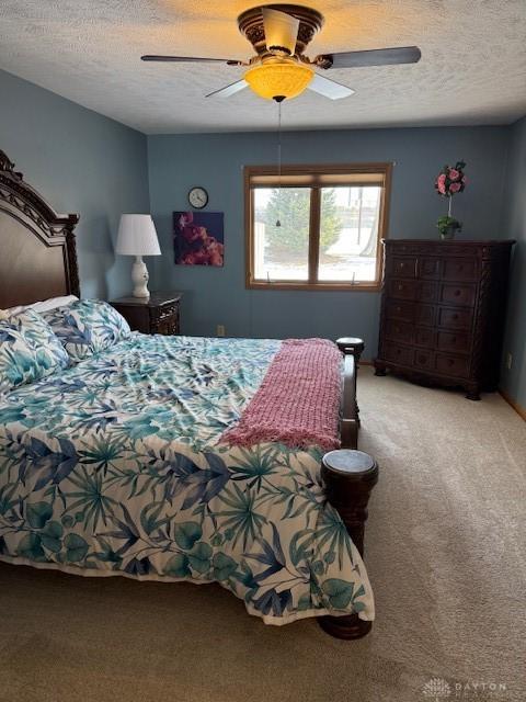 carpeted bedroom with a ceiling fan and a textured ceiling