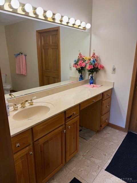 bathroom with toilet, baseboards, and vanity