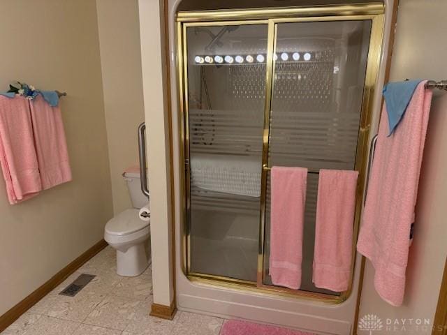 full bath featuring toilet, baseboards, visible vents, and a shower with shower door