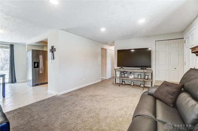 living room with light carpet, a textured ceiling, baseboards, and light tile patterned floors