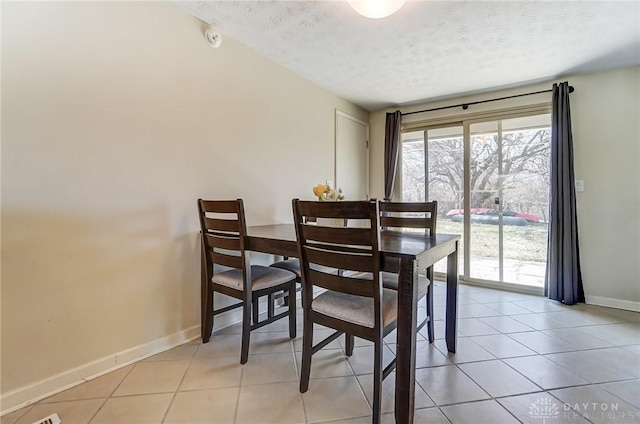 dining area featuring light tile patterned floors, plenty of natural light, baseboards, and a textured ceiling