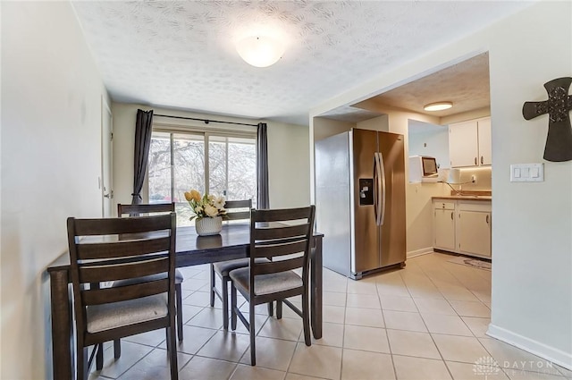 dining room with a textured ceiling, light tile patterned floors, and baseboards