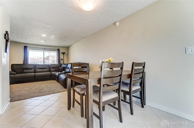 dining space with light tile patterned floors, a textured ceiling, and baseboards