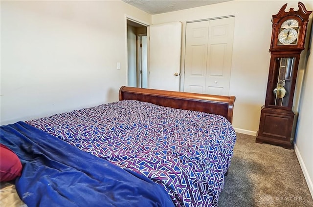 bedroom with a closet, dark carpet, and baseboards