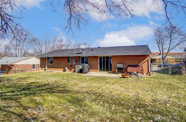 rear view of house with a yard, brick siding, a patio, and fence