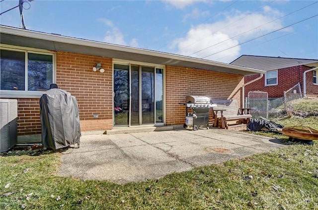 rear view of house featuring a patio area, fence, central AC, and brick siding