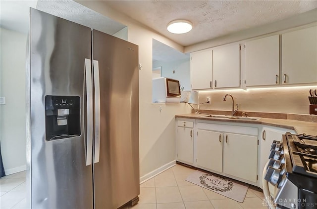 kitchen with appliances with stainless steel finishes, light countertops, white cabinetry, and a sink