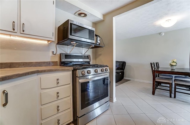 kitchen featuring visible vents, appliances with stainless steel finishes, white cabinetry, light tile patterned flooring, and baseboards