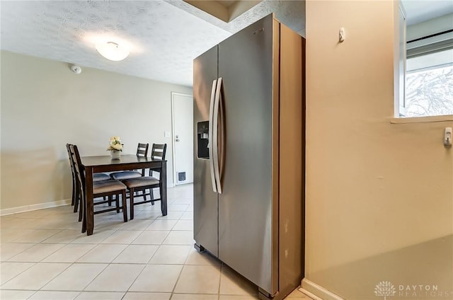 kitchen featuring stainless steel fridge, baseboards, a textured ceiling, and light tile patterned flooring