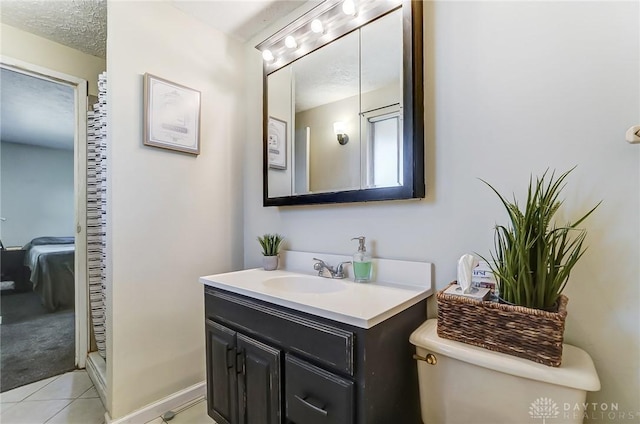 bathroom with ensuite bathroom, a textured ceiling, tile patterned flooring, toilet, and vanity