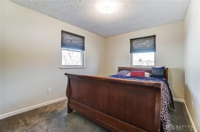 bedroom with a textured ceiling, dark colored carpet, and baseboards