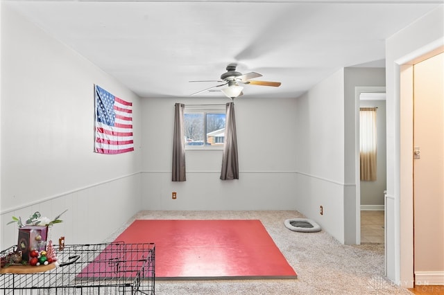 unfurnished room with wainscoting, a ceiling fan, and light colored carpet