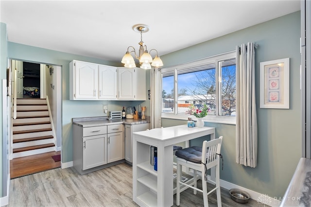 kitchen with hanging light fixtures, an inviting chandelier, light wood-type flooring, and light countertops