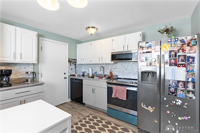 kitchen with a sink, white cabinetry, light countertops, appliances with stainless steel finishes, and light wood finished floors