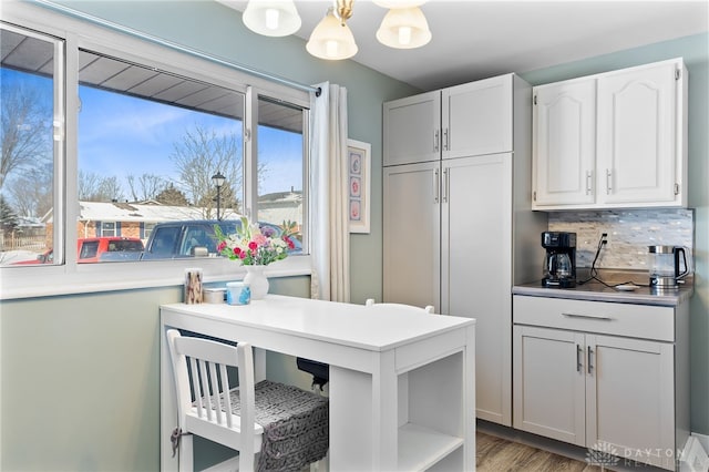 kitchen with open shelves, decorative backsplash, white cabinetry, wood finished floors, and a chandelier