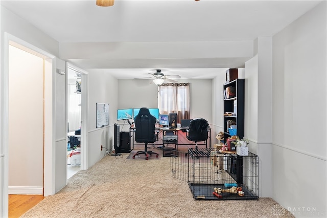 carpeted office with a ceiling fan