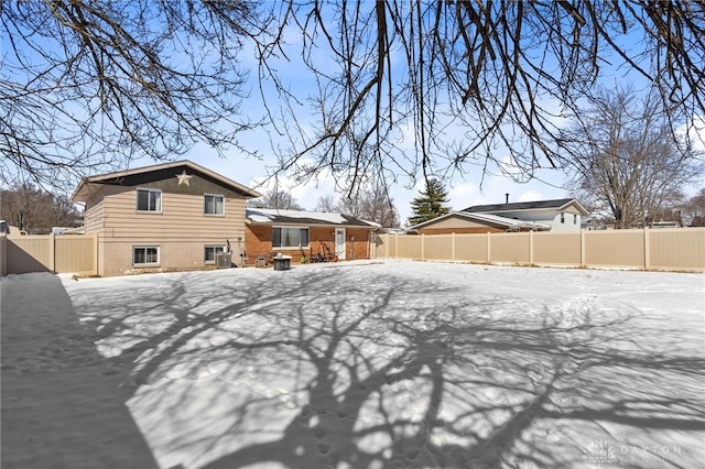 snow covered back of property featuring a fenced backyard