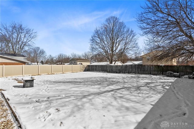 snowy yard featuring a fenced backyard