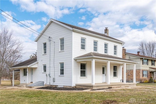 view of front of home with covered porch, roof with shingles, a chimney, and a front yard