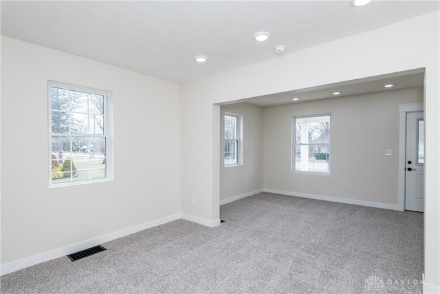 spare room with baseboards, visible vents, and light colored carpet