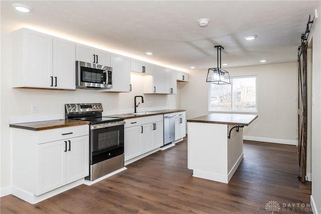 kitchen featuring white cabinets, a barn door, wood counters, and stainless steel appliances