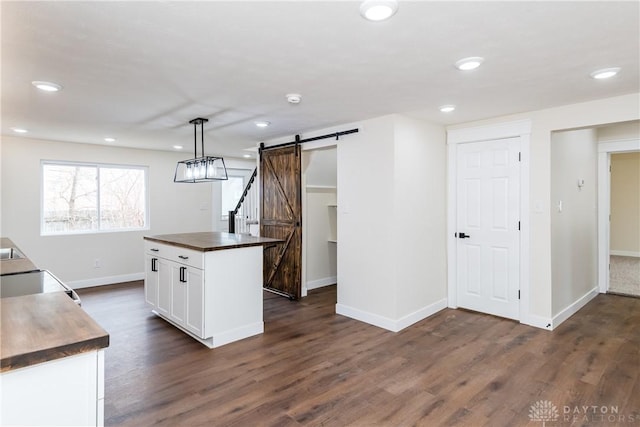 kitchen with pendant lighting, dark wood-style flooring, a barn door, white cabinets, and a kitchen island