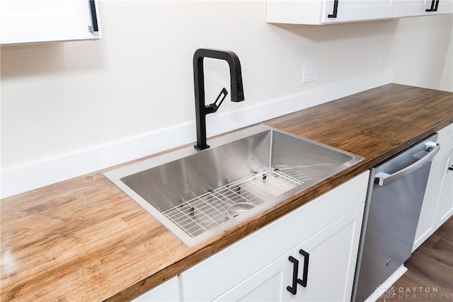 kitchen featuring dark wood-style flooring, white cabinetry, a sink, and stainless steel dishwasher