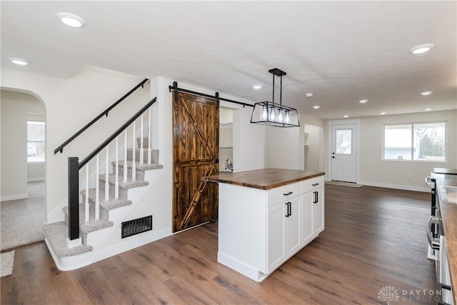 kitchen with pendant lighting, butcher block counters, a barn door, open floor plan, and white cabinets