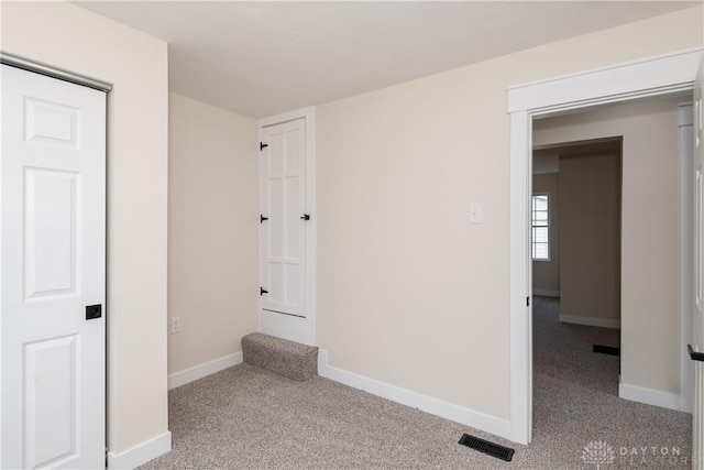 unfurnished bedroom featuring visible vents, baseboards, and light colored carpet