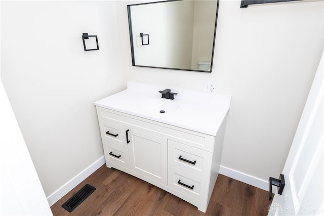 bathroom with baseboards, visible vents, wood finished floors, and vanity