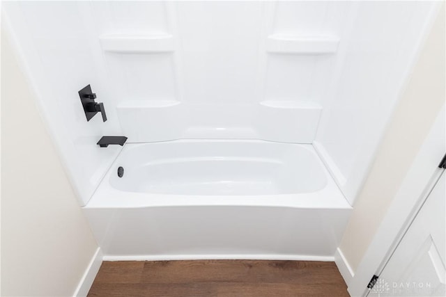 bathroom with wood finished floors, bathtub / shower combination, and baseboards