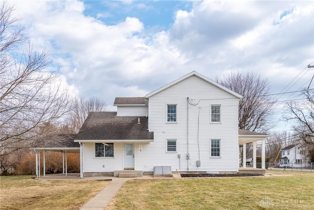 rear view of property featuring a shingled roof and a lawn