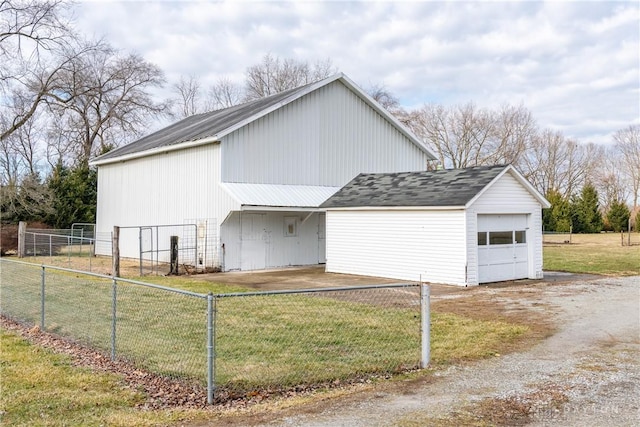 view of side of home featuring an outbuilding, a detached garage, fence, dirt driveway, and a lawn