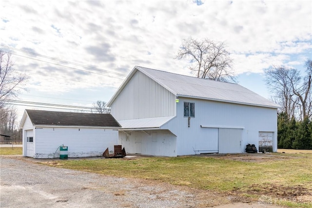 view of side of property with a garage, an outbuilding, and a yard