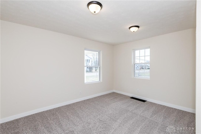 unfurnished room featuring carpet, visible vents, and baseboards