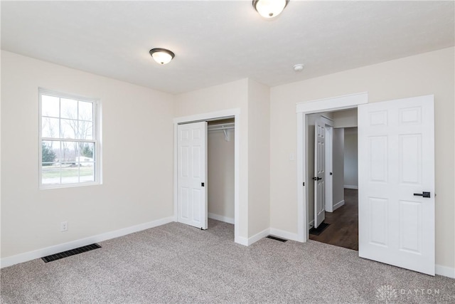 unfurnished bedroom with a closet, carpet, visible vents, and baseboards