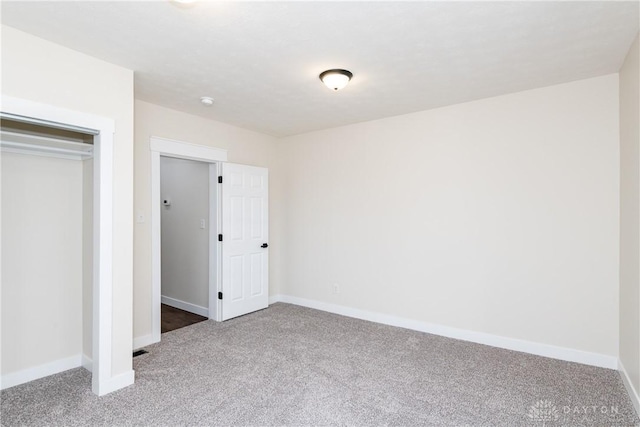 unfurnished bedroom with a closet, carpet, and baseboards