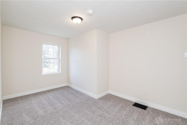 carpeted empty room featuring baseboards and visible vents