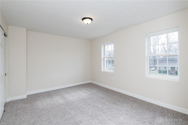 unfurnished room featuring carpet and baseboards