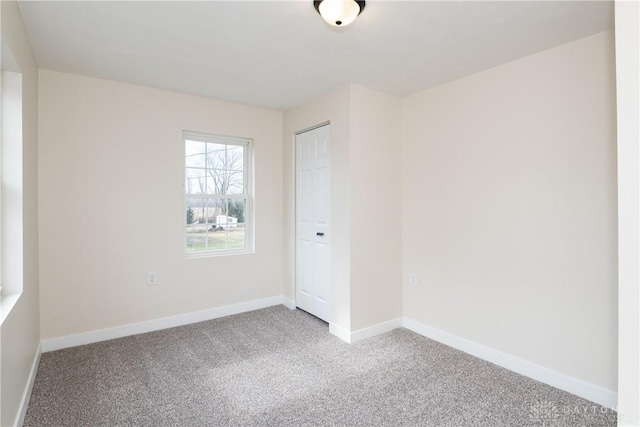 spare room featuring carpet and baseboards